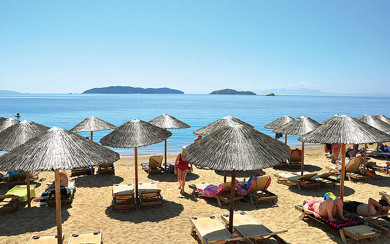 ein Bild des Achladis Strandes auf Skiathos mit Sonnenschirmen