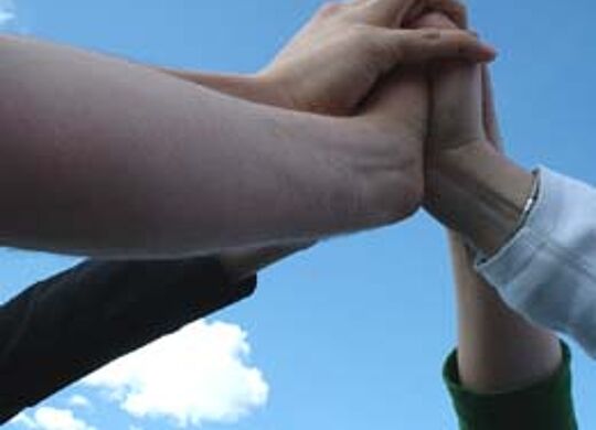 ein Bild mit verbundenen Händen, die Teamarbeit symbolisieren