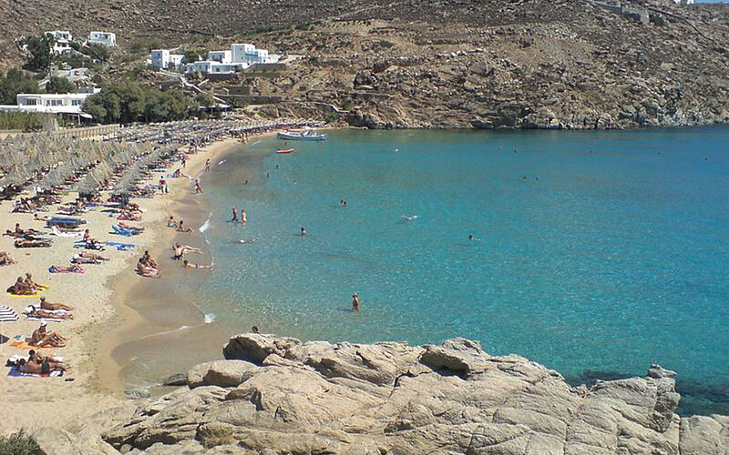 ein Bild des Super Paradise Strandes auf Mykonos mit Blick auf das Meer, den Strand und Hüglen bzw. Bergen