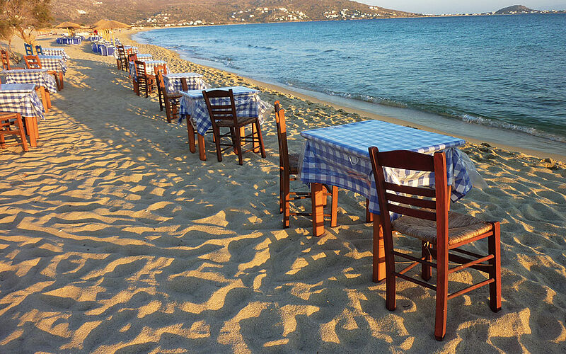 ein Bild mit Blick auf einen Strand auf Naxos mit Tischen und Stühlen