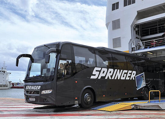 ein Bild eines schwarzen Buses mit dem Springer Logo